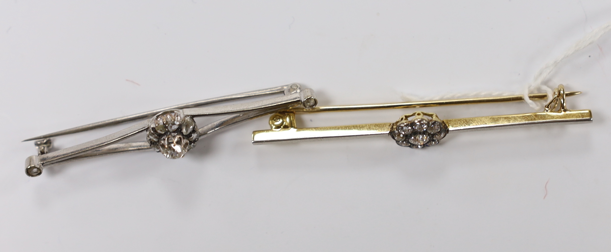An early to mid 20th century, yellow metal and nine stone diamond cluster set flower head bar brooch, 56mm and one other similar white metal and diamond cluster set flower head bar brooch, with diamond set terminals, gro